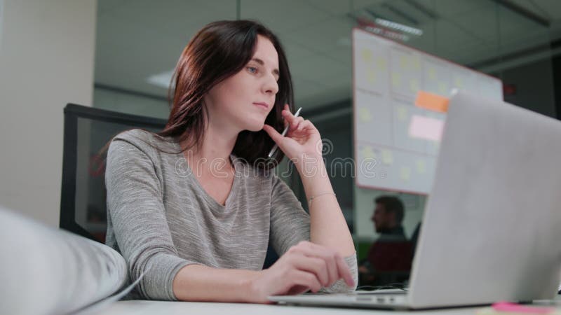 A Lady Sitting in the Office Working on a Laptop