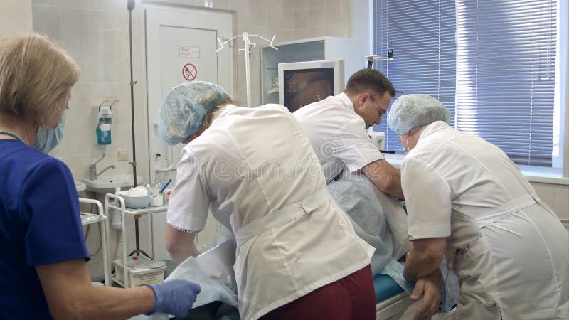 Lag av doktorer och sjuksköterskor som förbereder patienten för gastroscopy royaltyfria bilder Lag av doktorer och sjuksköterskor som förbereder patienten för gastroscopy royaltyfria bilder