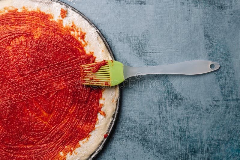 Laga mat italiensk pizza med tomater, höna, oliv på träbakgrund Tomatsås på degen vid kvinnas hand royaltyfria foton Laga mat italiensk pizza med tomater, höna, oliv på träbakgrund Tomatsås på degen vid kvinnas hand royaltyfria foton