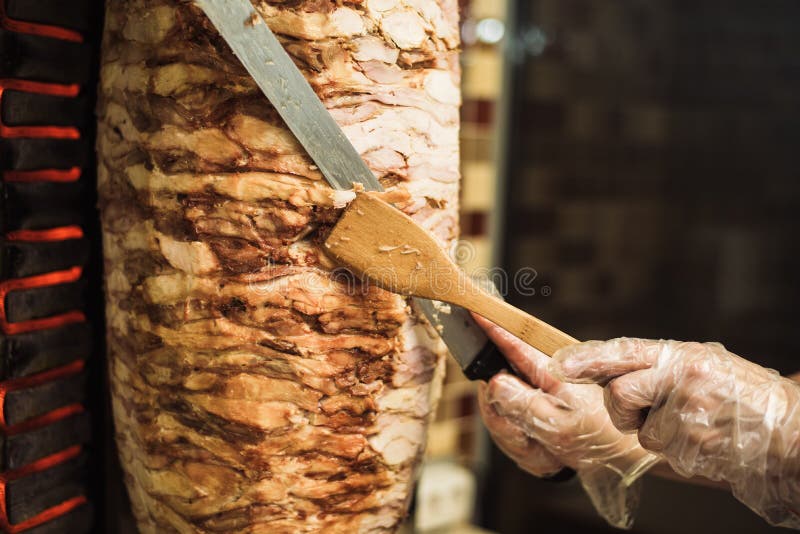 Laga mat shawarma och ciabatta i ett kafé En man i snittkött för disponibla handskar på en steknål royaltyfri foto Laga mat shawarma och ciabatta i ett kafé En man i snittkött för disponibla handskar på en steknål royaltyfri foto