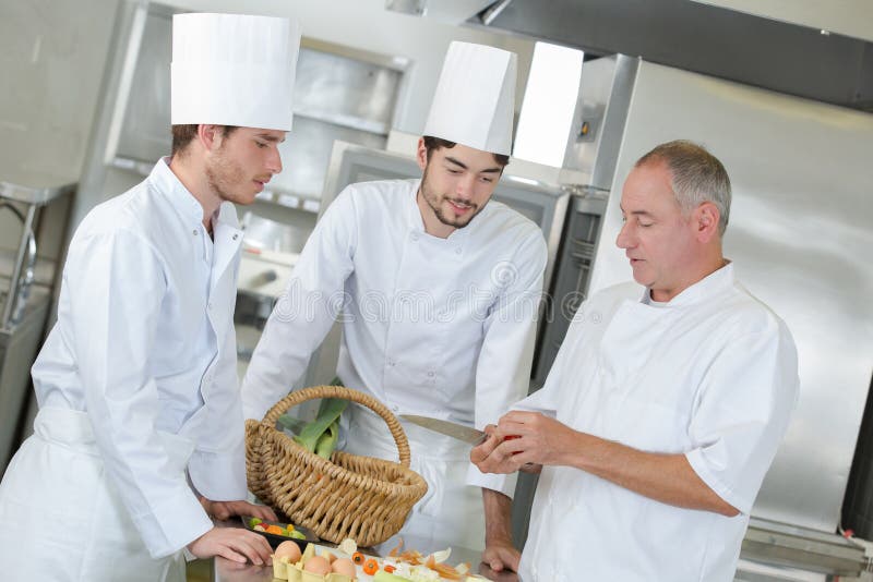 Lagar mat den positiva professionelln för besättningen arbete på restaurangkök arkivfoton Lagar mat den positiva professionelln för besättningen arbete på restaurangkök arkivfoton
