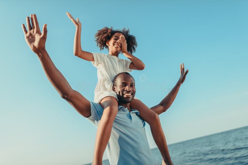 lage hoekmening van gelukkige Afrikaanse Amerikaanse vader dragende dochter en het hebben van pret
