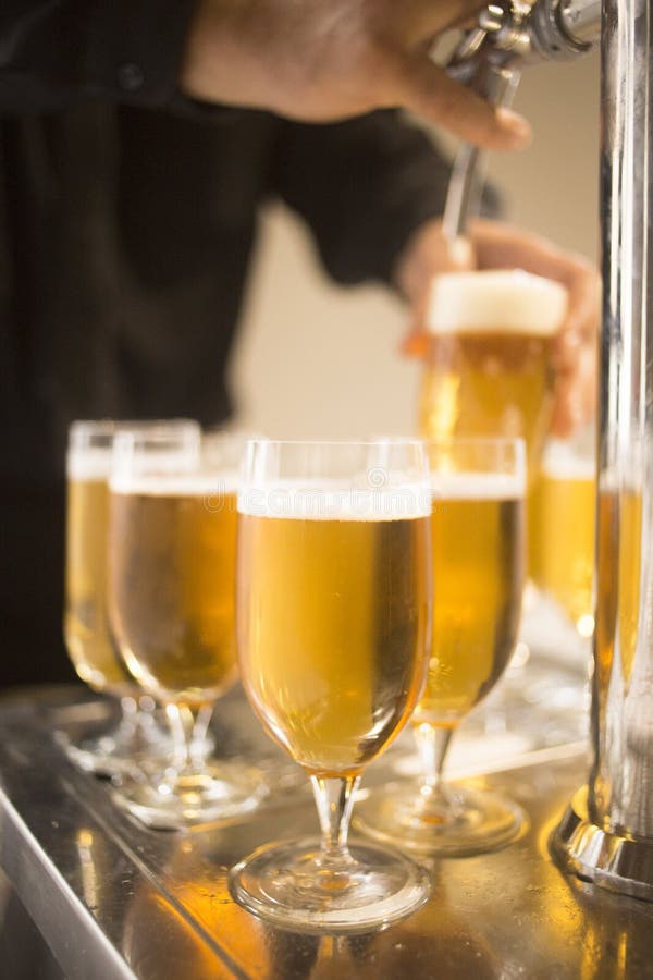 Lager draft beer glasses pump in restaurant bar. Lager draft beer glasses and beer pump tap in the light in a pub / public house restaurant bar. The multiple stock image Lager draft beer glasses pump in restaurant bar. Lager draft beer glasses and beer pump tap in the light in a pub / public house restaurant bar. The multiple stock image