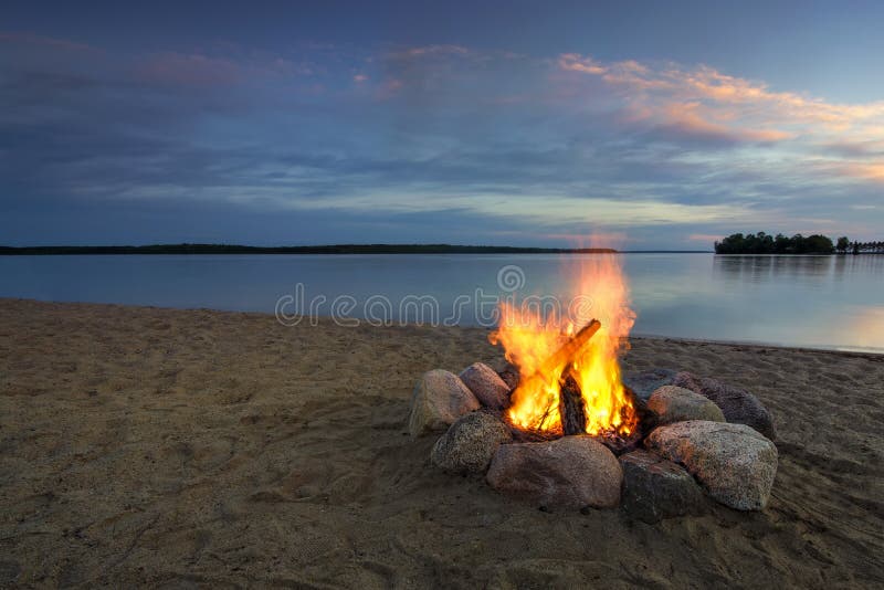 Lagerfeuer auf sandigem Strand, neben See bei Sonnenuntergang Minnesota, USA