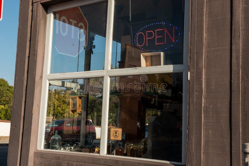 SAN JUAN BAUTISTA, CALIFORNIA, USA - OCTOBER 11, 2018: Glass of a store in the United States with a bright sign in which you can read open. SAN JUAN BAUTISTA, CALIFORNIA, USA - OCTOBER 11, 2018: Glass of a store in the United States with a bright sign in which you can read open