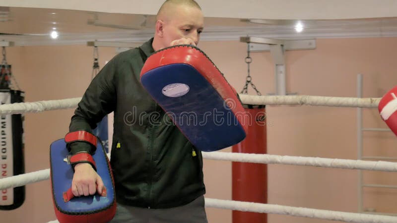 Lagledaren för en utbildningsstrid med tafsar med en kvinnlig kickboxer i cirkeln royaltyfria foton Lagledaren för en utbildningsstrid med tafsar med en kvinnlig kickboxer i cirkeln royaltyfria foton