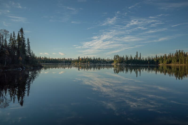 Lago ainda do norte ontario no amanhecer com clou refletido imagem de stock Lago ainda do norte ontario no amanhecer com clou refletido imagem de stock