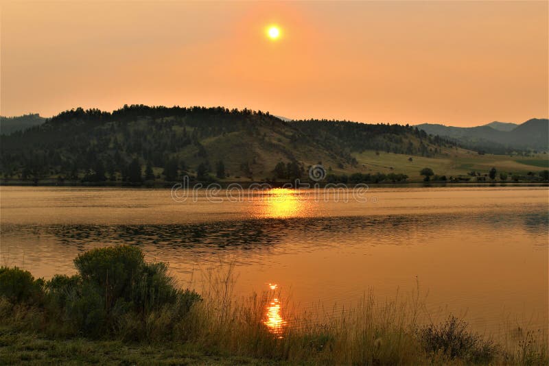 Lago arancio dorato dello specchio di alba della montagna del Montana fotografia stock Lago arancio dorato dello specchio di alba della montagna del Montana fotografia stock