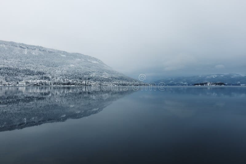 View to calm beautiful lake and mountains in foggy winter day. View to calm beautiful lake and mountains in foggy winter day.