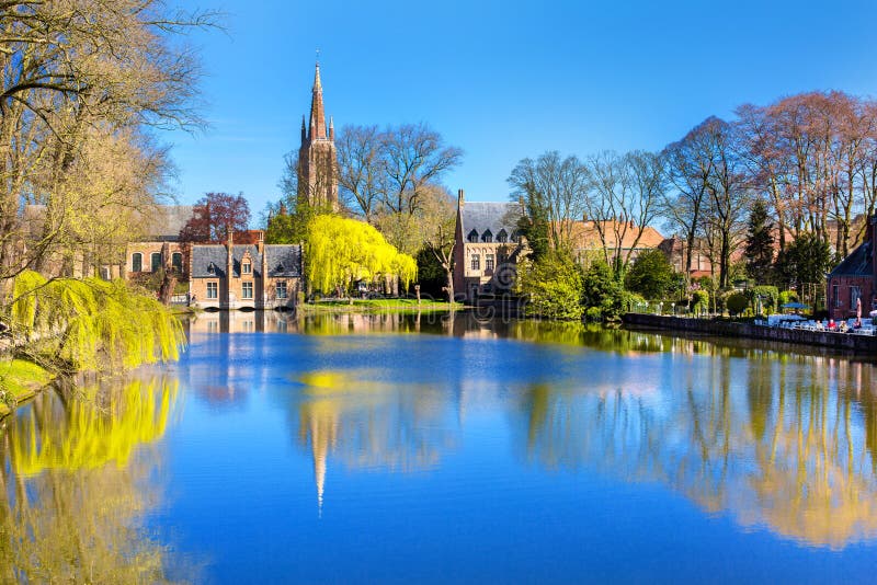 Lago em Bruges, em Bélgica, em igreja e na reflexão medieval das casas na água foto de stock Lago em Bruges, em Bélgica, em igreja e na reflexão medieval das casas na água foto de stock