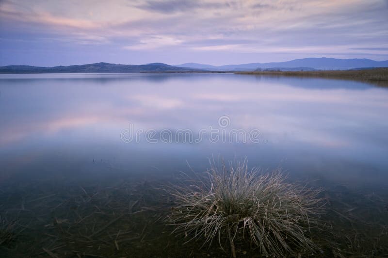 Lago en la igualación después de puesta del sol con la exposición larga foto de archivo Lago en la igualación después de puesta del sol con la exposición larga foto de archivo