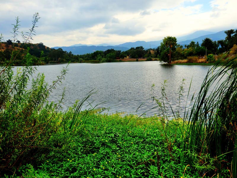 Bela foto de um moinho de vento perto do lago sob um céu nublado