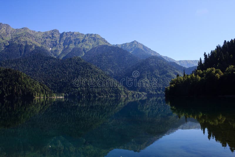 Lago Ritsa circondato con le alte montagne di Caucaso che si rispecchiano in acqua fotografie stock libere da diritti Lago Ritsa circondato con le alte montagne di Caucaso che si rispecchiano in acqua fotografie stock libere da diritti
