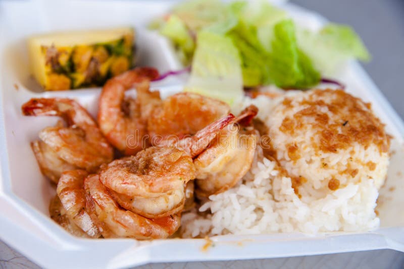 Photo of popular seafood dish called shrimp scampi. This is butterflied deveined shrimp marinated in a sauce of butter, garlic, lemon, and parsley then baked in a casserole dish or placed on a cookie sheet lined with parchment paper. The shrimp may be put under the broiler for the final moments of cooking then are served on top of a bed of rice and garnished with lemon. Photo of popular seafood dish called shrimp scampi. This is butterflied deveined shrimp marinated in a sauce of butter, garlic, lemon, and parsley then baked in a casserole dish or placed on a cookie sheet lined with parchment paper. The shrimp may be put under the broiler for the final moments of cooking then are served on top of a bed of rice and garnished with lemon.