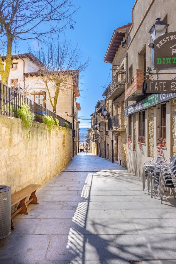 Laguardia, Alava, Espanha 30 de março de 2018: A rua com o assoalho do grande bloco de pedra regular do granito e os diversos caf fotos de stock Laguardia, Alava, Espanha 30 de março de 2018: A rua com o assoalho do grande bloco de pedra regular do granito e os diversos caf fotos de stock
