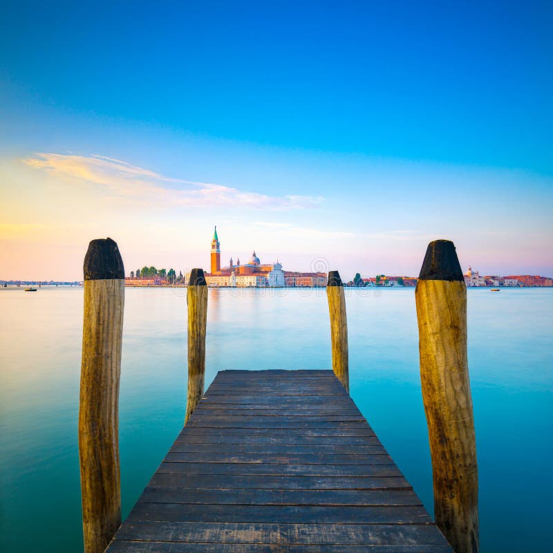 Lagune de Venise, pilier ou jetée en bois et poteaux et église sur le CCB photographie stock libre de droits Lagune de Venise, pilier ou jetée en bois et poteaux et église sur le CCB photographie stock libre de droits