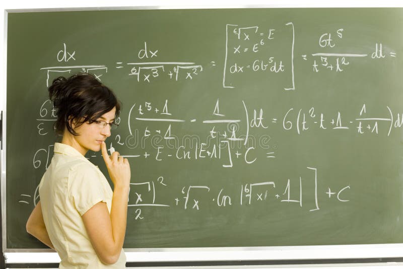 Teenage girl standing in classroom. Doing exercise on blackboard. Side view. Teenage girl standing in classroom. Doing exercise on blackboard. Side view