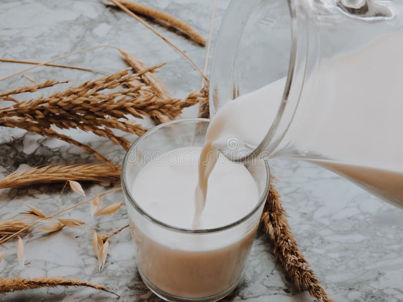 Lait se renversant dans le verre sur le fond bleu E Front View r photo stock Lait se renversant dans le verre sur le fond bleu E Front View r photo stock