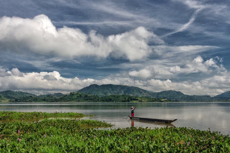 LAK VIET NAM DE DAK: El grupo de granjero asiático va a trabajar en barco de fila en el lago en tiempo del otoño, familia de mino imagen de archivo LAK VIET NAM DE DAK: El grupo de granjero asiático va a trabajar en barco de fila en el lago en tiempo del otoño, familia de mino imagen de archivo