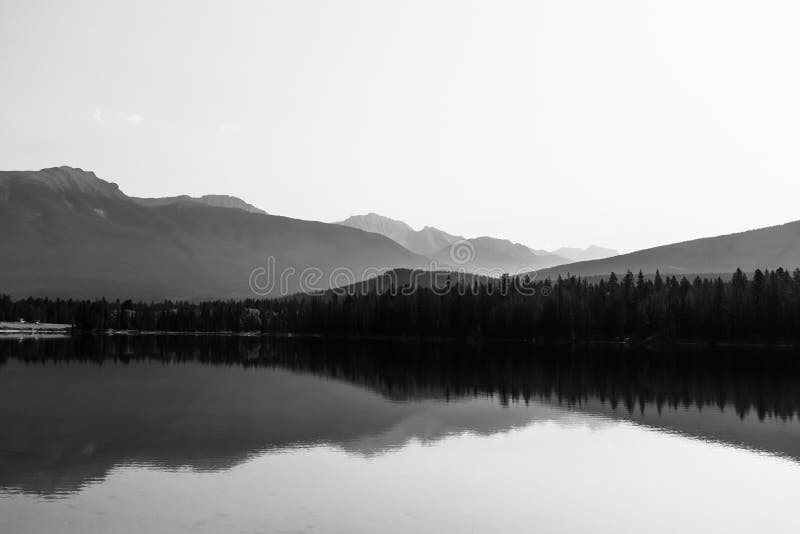 Mountain range reflecting in a calm mirror-like water surface of the Lake Annette near Jasper, Alberta, Canada.