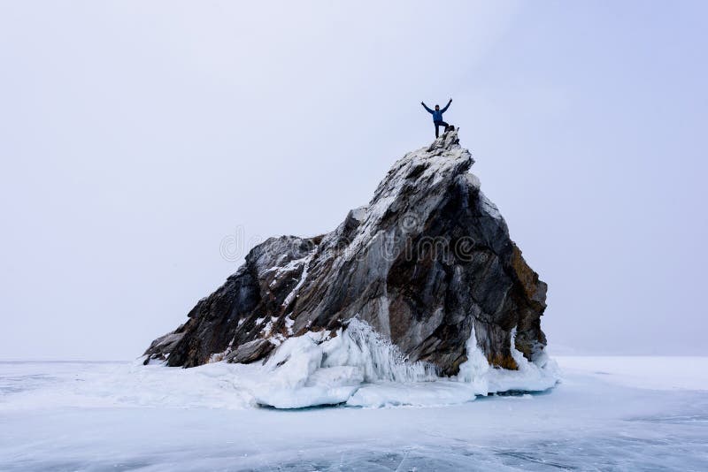 Lake Baikal, Russia - March 9, 2020: Rock climber on the top of mountain island. Sport and active life