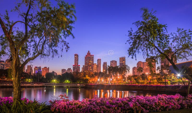 Lake in City Park under Skyscrapers at Night. Benjakiti Park in Bangkok, Thailand