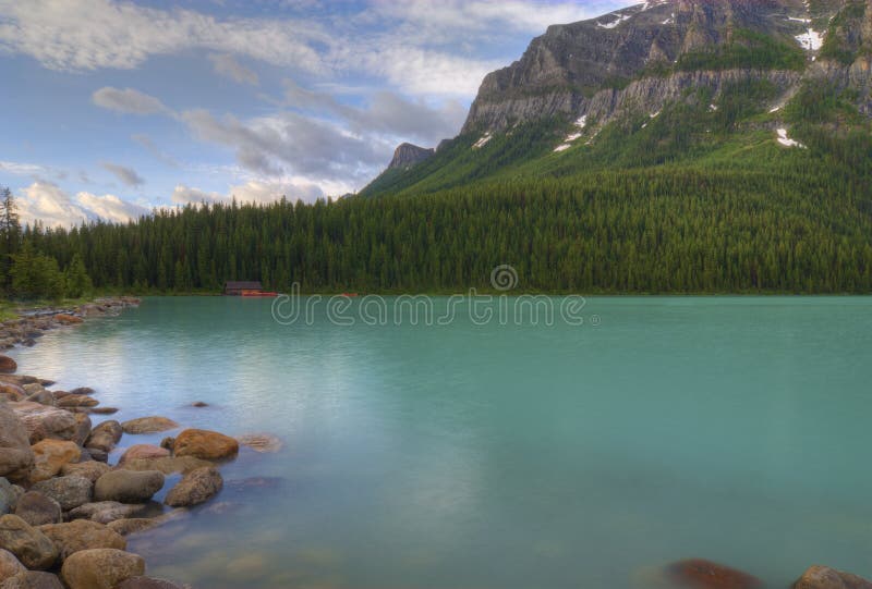 The incredible turquoise blue water of Lake Louise in Banff National Park in Alberta Canada. The amazing color is natural and is caused by light reflecting on the rock flower which is suspended in the water. The glaciers grind up the rock as they move and then the melt water carries the rock flower into the lake.