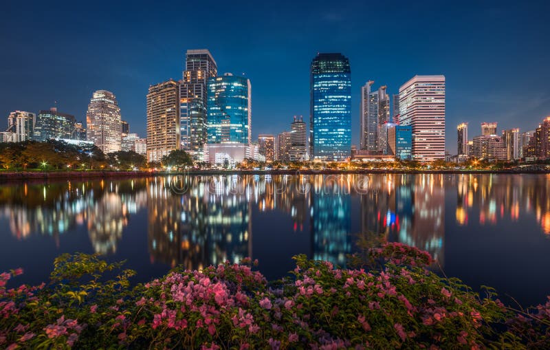 Lake with Purple Flowers in City Park under Skyscrapers at Night. Benjakiti Park in Bangkok, Thailand