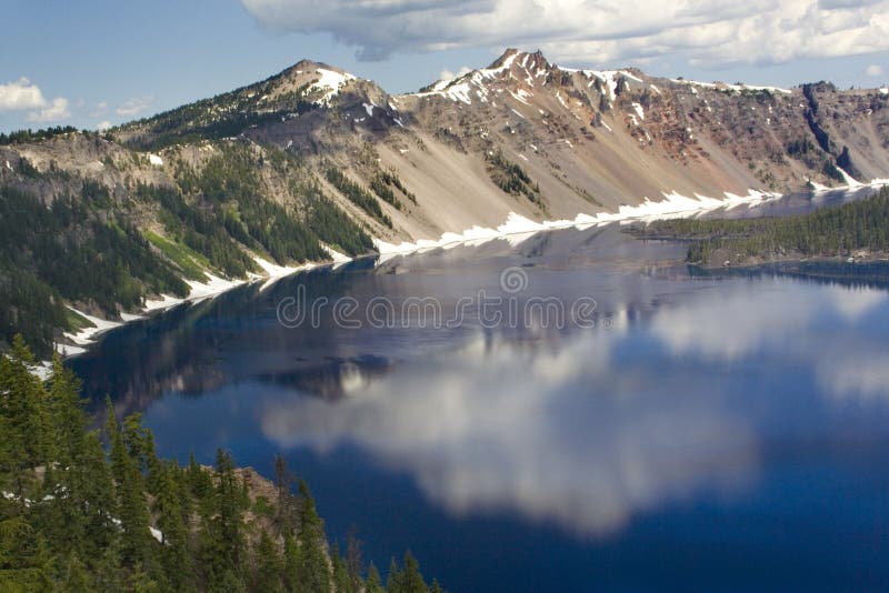 Clouds and mountains reflected in the blue water of Crater Lake (National Park) in Oregon, USA. Clouds and mountains reflected in the blue water of Crater Lake (National Park) in Oregon, USA.