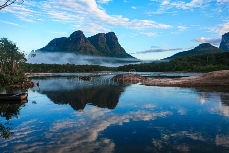 Lake With A Rock Formation Visible In The Still Waters And Foggy Lake With A Rock Formation Visible In The Still Waters And Foggy