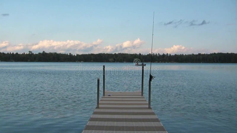 Lake scene with dock, fishing pole and fishing boat