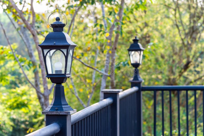 Lamp on the black metal balcony with natural green tree gardening exterior for home and living achitecture decoration. Vintage ant