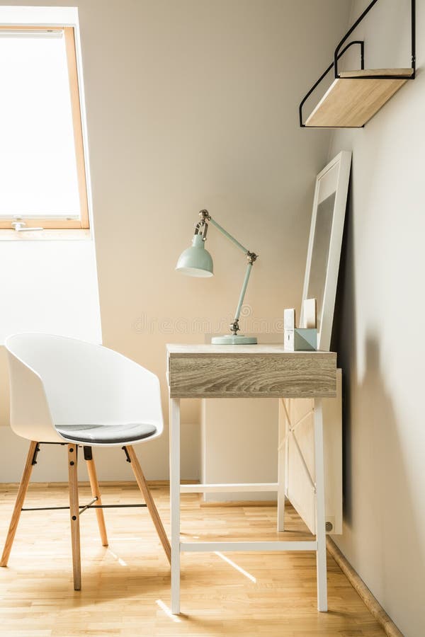 Lamp on desk in white workspace interior on attic with chair and