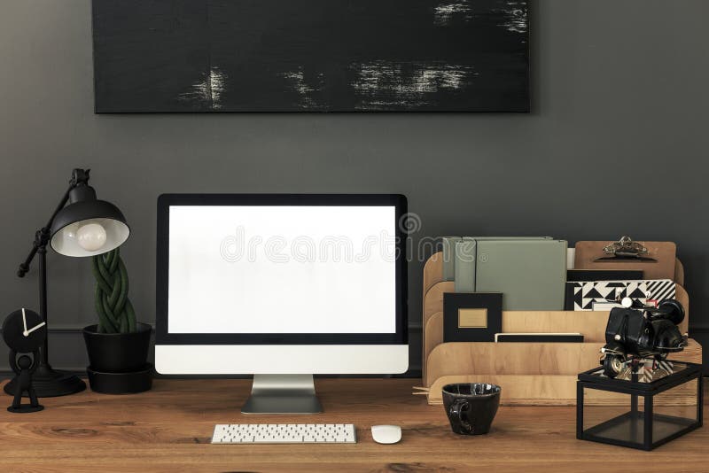 Lamp and organizer on wooden desk in grey home office interior with mockup. Real photo