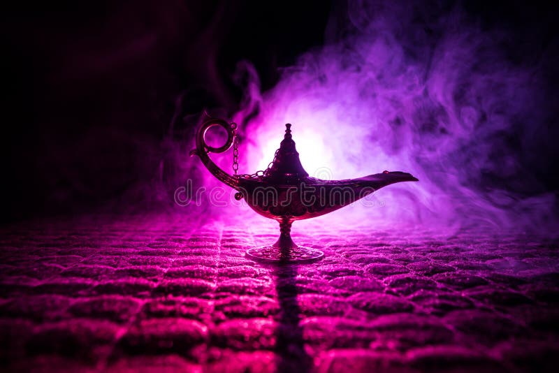 Lamp of wishes concept. Antique Aladdin arabian nights genie style oil lamp with soft light white smoke, Dark background