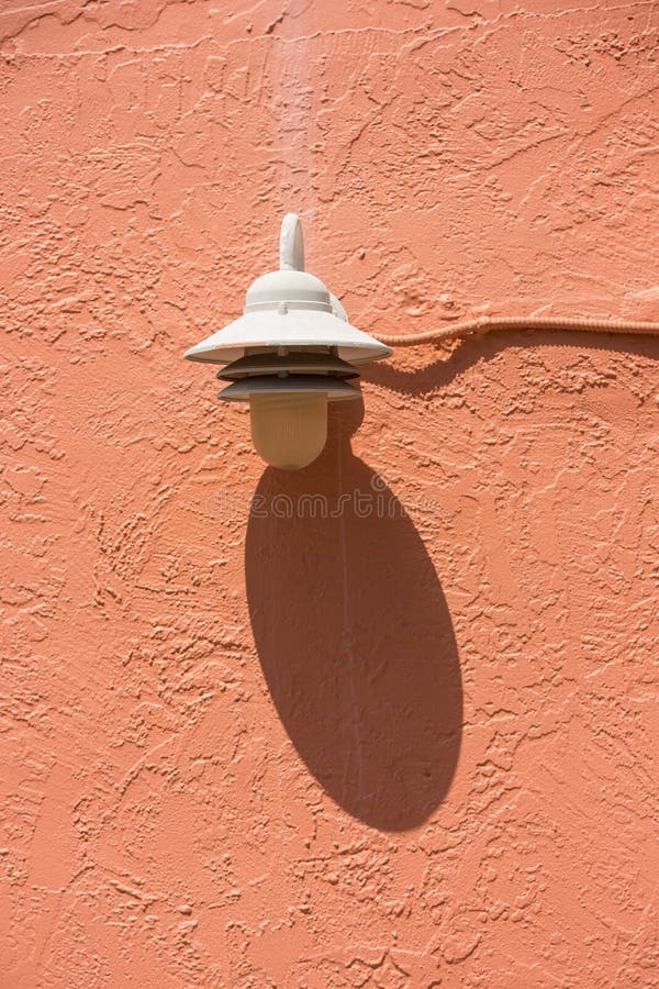 Lampada bianca con ombra sulla parete arancio dello stucco immagini stock libere da diritti Lampada bianca con ombra sulla parete arancio dello stucco immagini stock libere da diritti