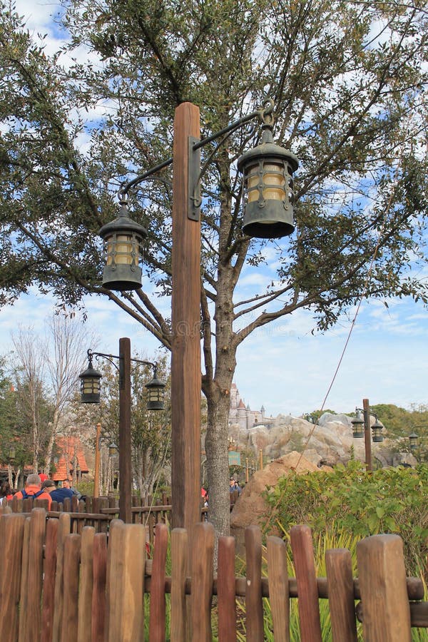 Old fashioned mining style exterior lamps and post in front of a tree and white cloud studded blue sky in the background. Disney, Orlando, Florida. Old fashioned mining style exterior lamps and post in front of a tree and white cloud studded blue sky in the background. Disney, Orlando, Florida.