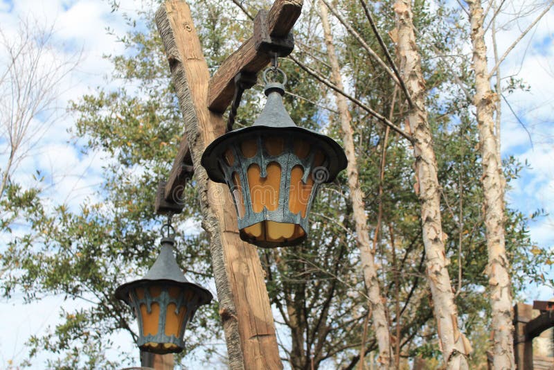 Old fashioned antique style exterior lamps and post in front of a tree and white cloud studded blue sky in the background. Disney, Orlando, Florida. Old fashioned antique style exterior lamps and post in front of a tree and white cloud studded blue sky in the background. Disney, Orlando, Florida.