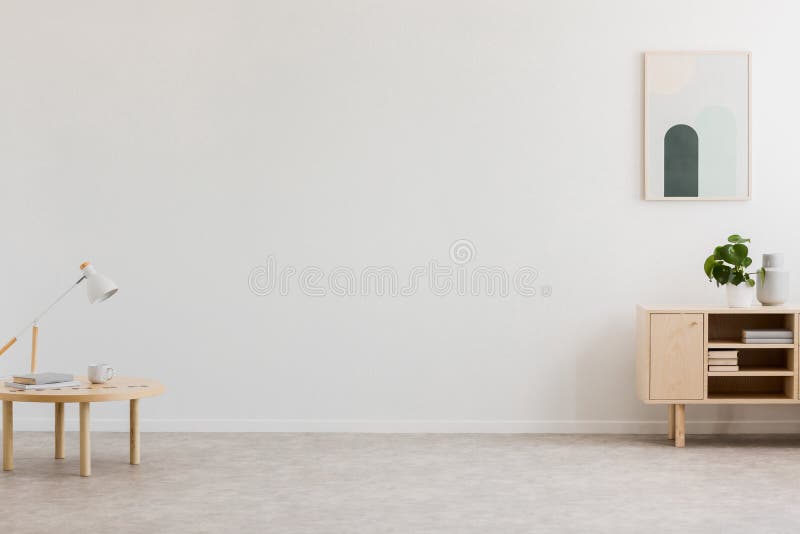 Lampe de bureau sur une petite table et un coffret simple et en bois dans un intérieur vide de salon avec le mur blanc et l'endro images stock