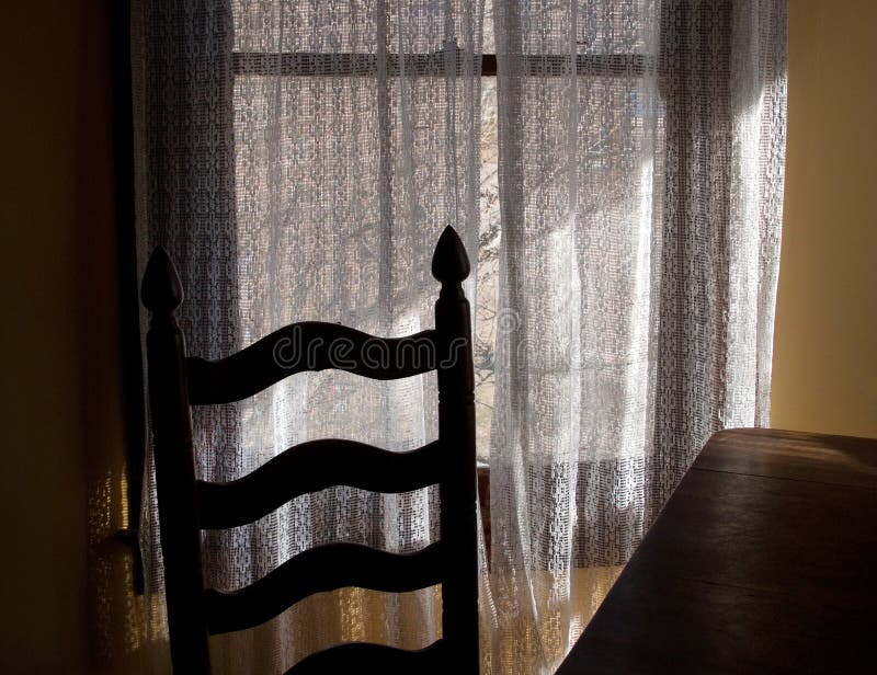 Old chair and table against a window with lace curtains. Old chair and table against a window with lace curtains