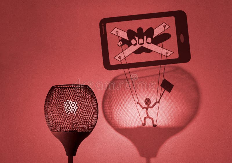 Gaslight with silhouette of puppet on strings being manipulated by a hand in mobile phone cast by the lamp on wall, social media gaslighting concept illustration. Gaslight with silhouette of puppet on strings being manipulated by a hand in mobile phone cast by the lamp on wall, social media gaslighting concept illustration