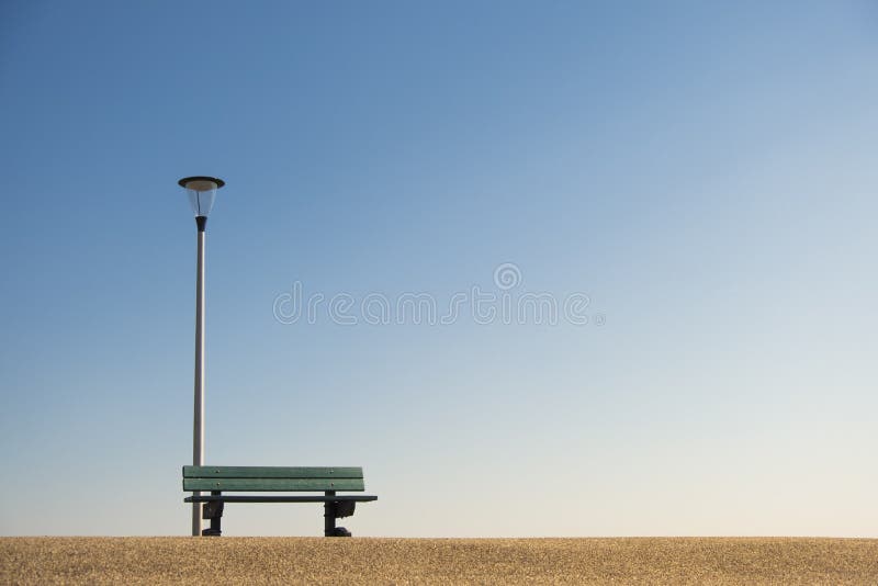 Lamppost com banco no asfalto contra um céu azul fotos de stock Lamppost com banco no asfalto contra um céu azul fotos de stock