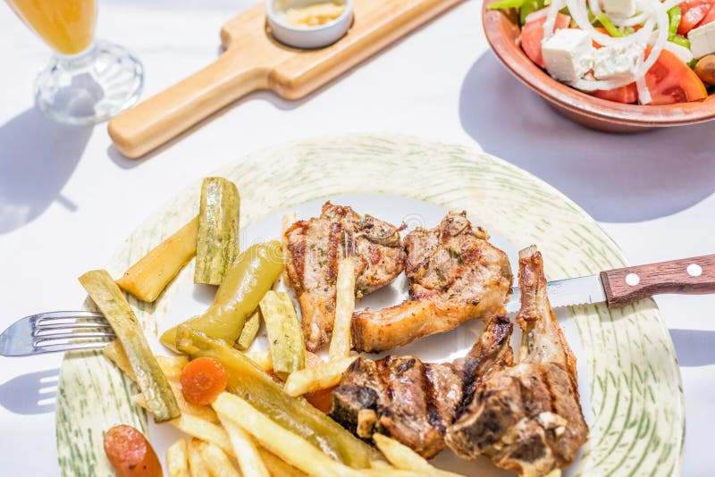 Lamskoteletten met groenten en braadstukaardappels op een plaat in een Griekse restaurant of een herberg royalty-vrije stock afbeeldingen Lamskoteletten met groenten en braadstukaardappels op een plaat in een Griekse restaurant of een herberg royalty-vrije stock afbeeldingen