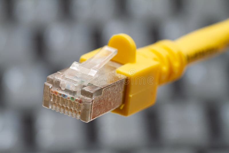 LAN network cable in yellow with a keyboard background .