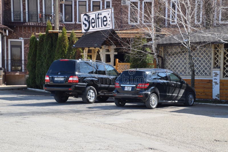 Landa kryssaren Prado från Toyota och Mercedes b200 Bilen parkeras nära kafét fotografering för bildbyråer Landa kryssaren Prado från Toyota och Mercedes b200 Bilen parkeras nära kafét fotografering för bildbyråer