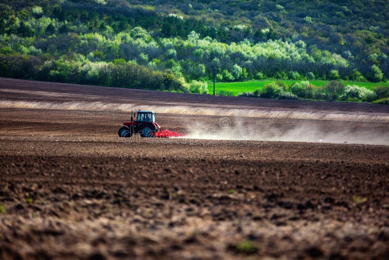 Landbouwer met tractor het zaaien gewassen bij gebied royalty-vrije stock afbeelding Landbouwer met tractor het zaaien gewassen bij gebied royalty-vrije stock afbeelding
