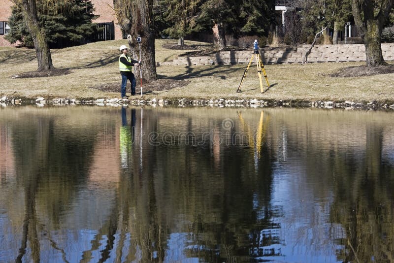 Land Surveyor and his instrument reflected in the pond. Land Surveyor and his instrument reflected in the pond.