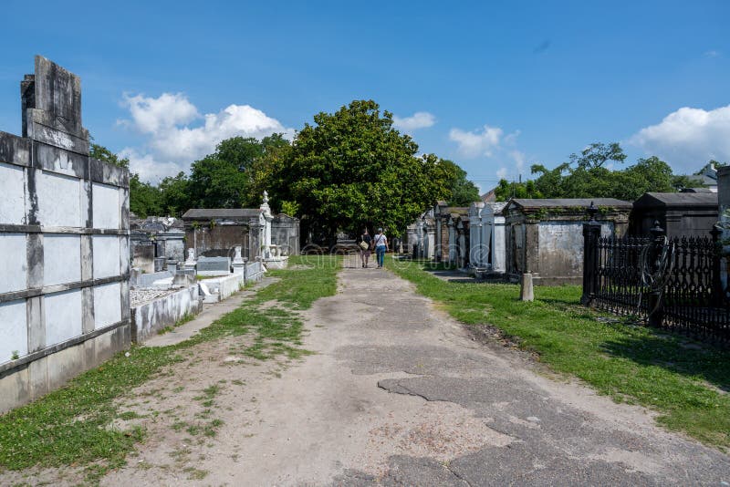 New Orleans, LA, USA -- May 26, 2019.  Wide angle landscape photo of  St Louis Cemetery #3; couple in the distance walks along a path. New Orleans, LA, USA -- May 26, 2019.  Wide angle landscape photo of  St Louis Cemetery #3; couple in the distance walks along a path