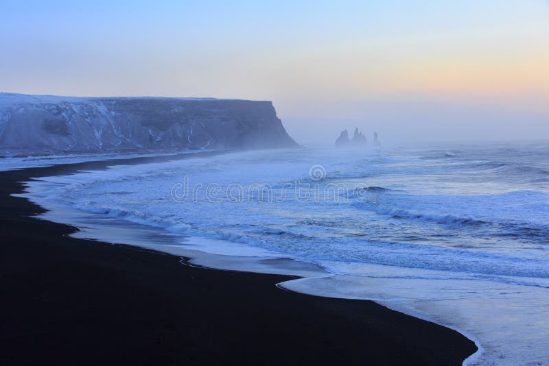 Landscape with beach of black sand and the sea stacks in the background