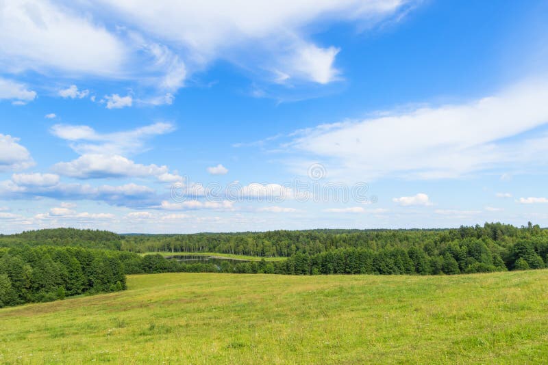 Landscape of European plains with hills and lowlands, marshes, meadows and forests. Cloudy Blue sky over horizon